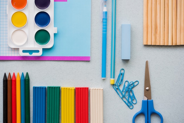 Buona preparazione per le materie scolastiche. accessori per la scuola di plastilina colorata, matite colorate, penna a forbice con graffetta e colori ad acquerello. vista dall'alto