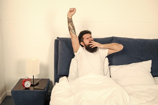 Фото Хороший отдых заряжен и полон энергии здоровый сон отдых на выходных мужчина потягивается в постели беззаботный парень наслаждается утром проснись наслаждаясь беззаботным утром ленивый мужчина счастлив проснуться в постели