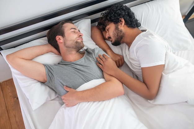 Good sleep. two young men in bed sleeping and looking
relaxed