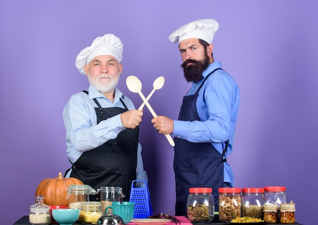 Photo good team cereals and seasoning professional restaurant cook halloween pumpkin recipe chef men cooking cheerful men prepare food mature senior bearded men in kitchen healthy food cooking