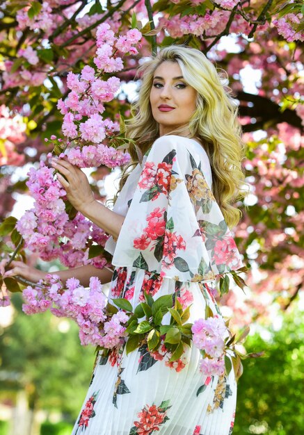 Goodlooking gardener soft skin care healthy girl in cherry tree garden vintage summer fashion spring nature blossom in park retro woman smell sakura flowers spa and beauty treatment