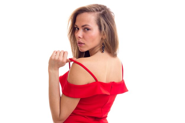 Goodlooking young woman with long brown  hair in skimpy red dress with black earings in studio