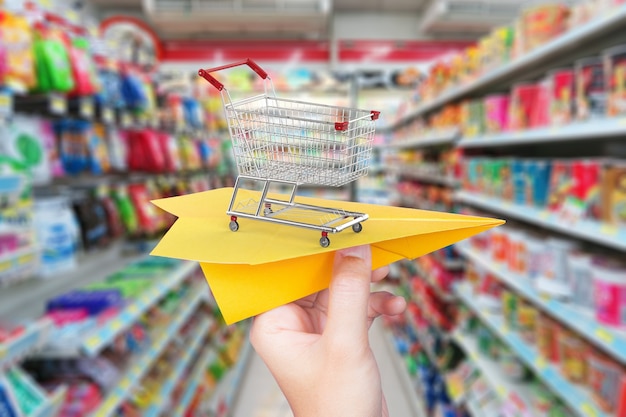 Goods delivery concept with paper plane and 3d rendering shopping cart in supermarket