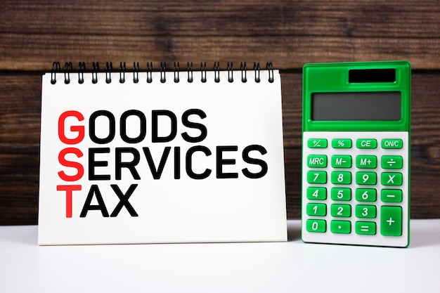 Goods Service Tax text on notepad next to calculator Tax on goods and services business financial concept