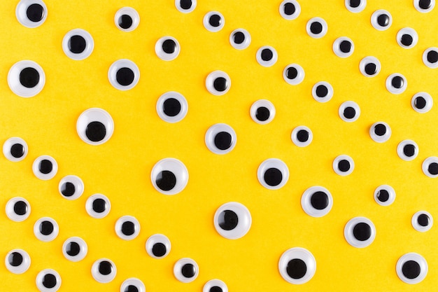 Googly plastic ogenpatroon op gele backgroud. plat liggen.