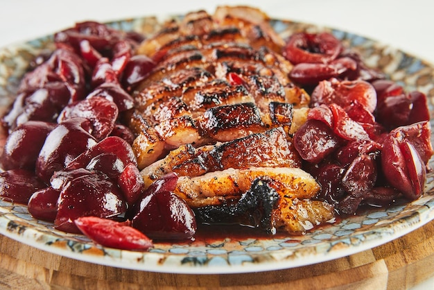 Goose brisket with cherries served on plate on wooden background Close up