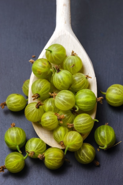 Photo gooseberry in big wooden spoon