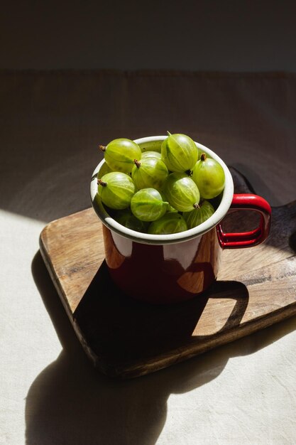 Gooseberry in a red enamel mug and natural sunlight