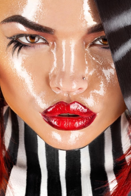 Gorgeous adult woman with wet face and stripes on neck and hair in studio