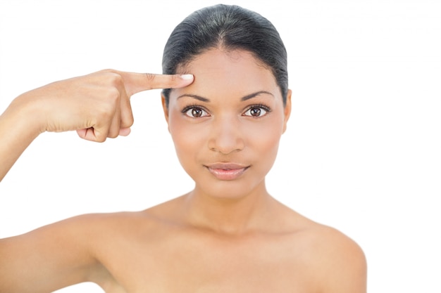 Gorgeous black haired model pointing at her forehead