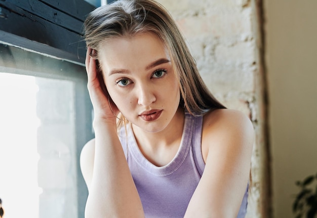 Gorgeous blond teenage girl in violet tanktop looking at camera in studio