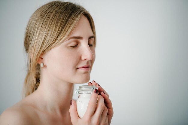 Gorgeous blonde woman holding bottle of moisturizer