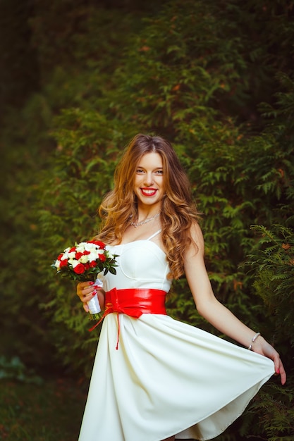 Gorgeous blonde woman in white short dress with red bow posing