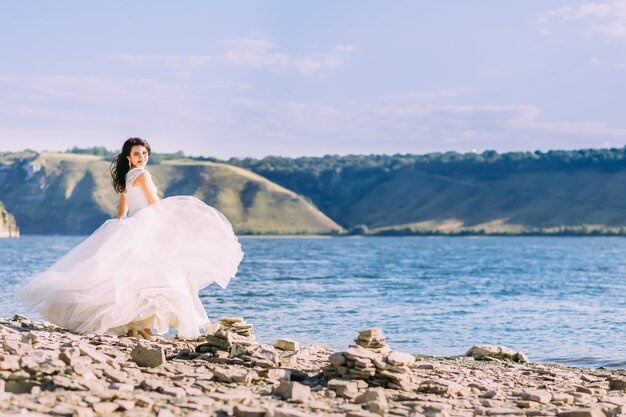 Gorgeous bride in luxury white dress standing at the bay smiling