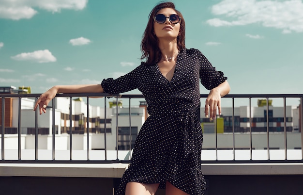 Gorgeous bright brunette woman in fashion dress posing on the roof of a building