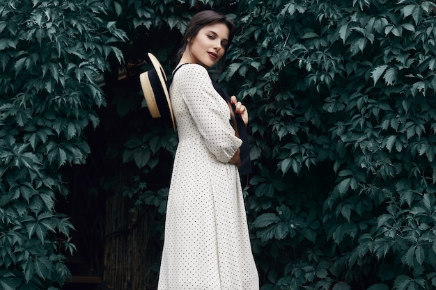 Gorgeous bright brunette woman in fashion dress with straw hat