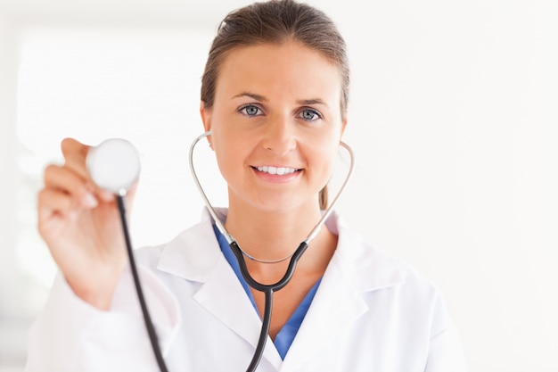 Gorgeous brunette doctor showing stethoscope looking into the ca