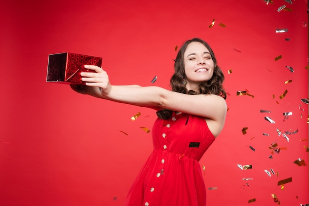 Gorgeous brunette girl in red dress in confetti.