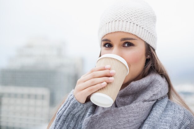 コーヒーを飲む際の冬の服を着た豪華なブルネット