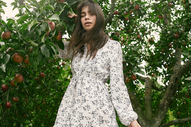 Gorgeous brunette woman in fashion classic dress in apple garden