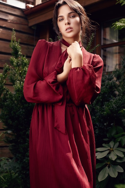 Великолепная брюнетка в моде красное платье в саду