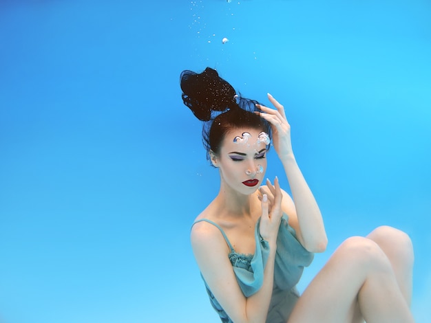 gorgeous brunette young woman with make up underwater in the swimming pool