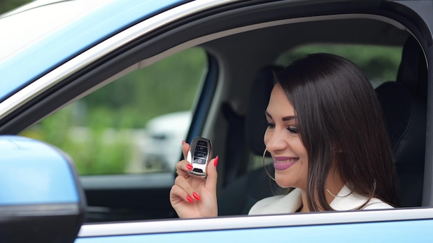 Gorgeous businesswoman driver shows key to new car smiling