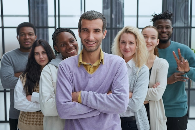 Gorgeous casual man in purple shirt standing with hands on hip looking forward happily