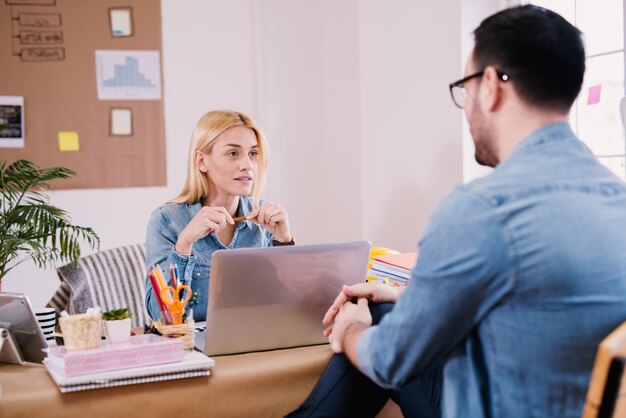 Gorgeous charming confident entrepreneur woman having the interview or conversation with a young man in the office.