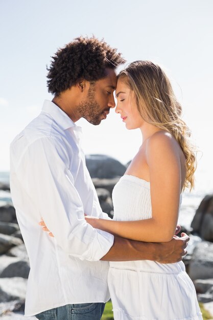 Gorgeous couple embracing by the coast on a sunny day