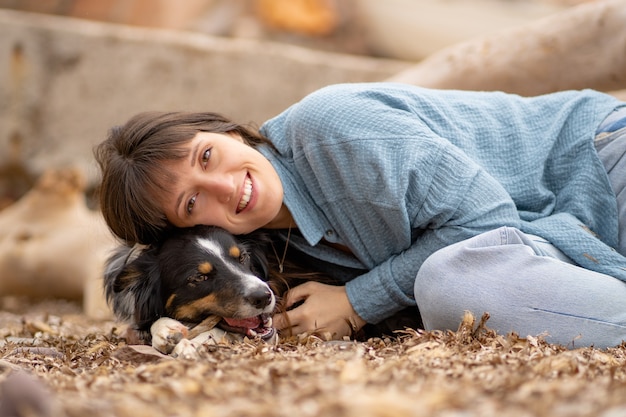 Gorgeous fair skinned girl lying on her dog on the beach with smile