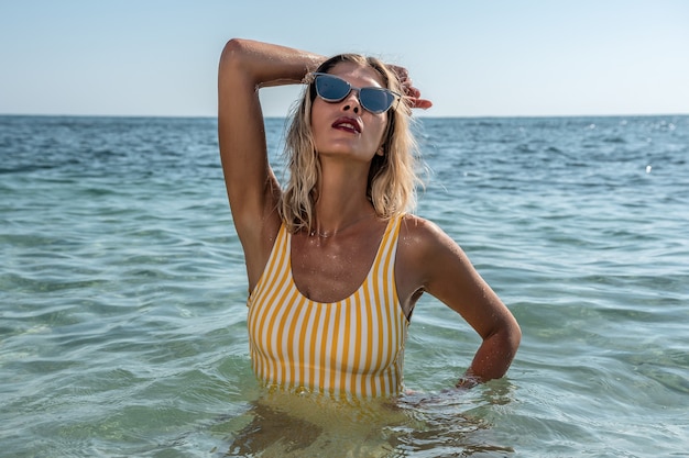 Gorgeous fashion model posing in the calm sea.