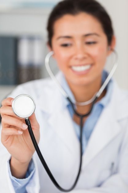 Medico femminile splendido che per mezzo di uno stetoscopio mentre esaminando la macchina fotografica