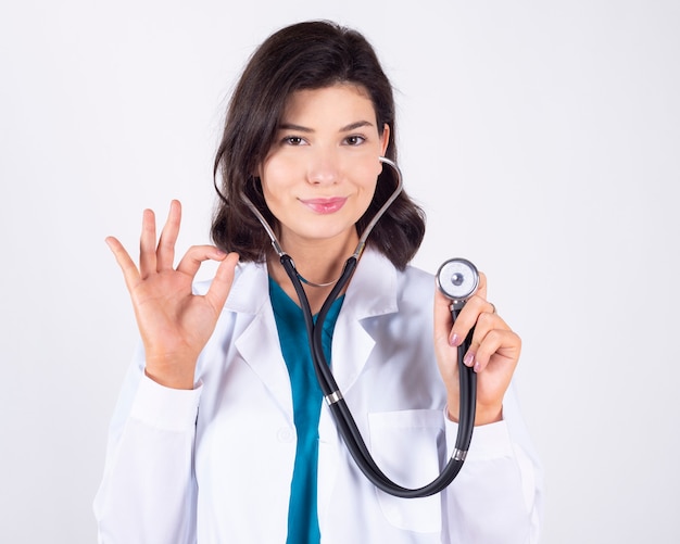 Gorgeous female doctor using a stethoscope on white space