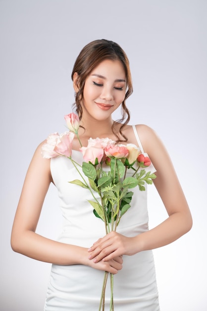 Gorgeous female model with fair skin and perfect makeup holding flowers