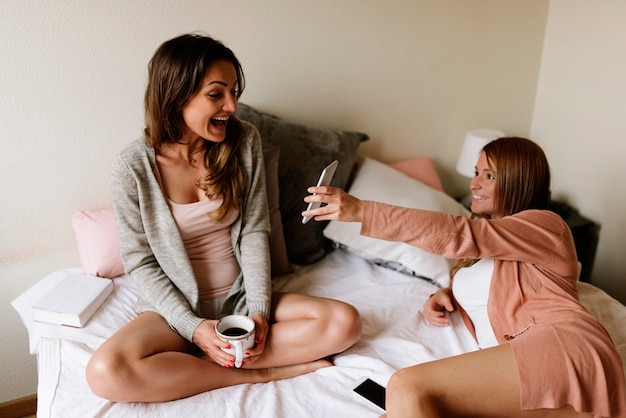 Gorgeous friends chatting in the bedroom. Best friend concept.