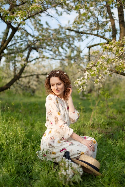 Una bellissima ragazza cammina in un giardino fiorito primaverile. il concetto di unità dell'uomo con la natura