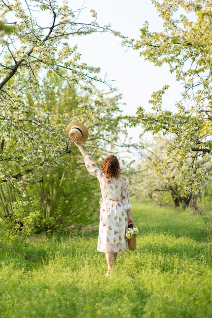 A gorgeous girl walks in a flowering spring garden