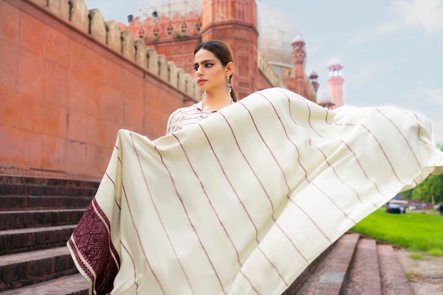 Photo gorgeous girl waving dupatta badshahi mosque in background