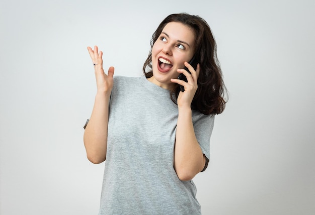 Gorgeous girl with a phone in her hand is astonished by something she sees away