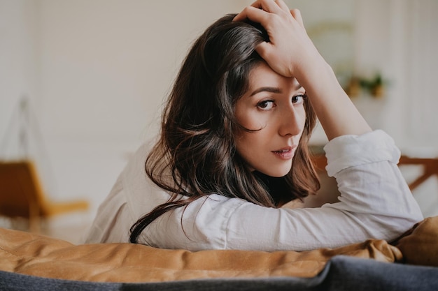 Gorgeous hispanic brunette woman in glasses with wavy loose hair in white shirt looking at diary