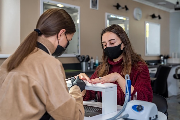 Gorgeous manicure master in special black gloves works on the girl's nails Beauty salon concept Manicure concept