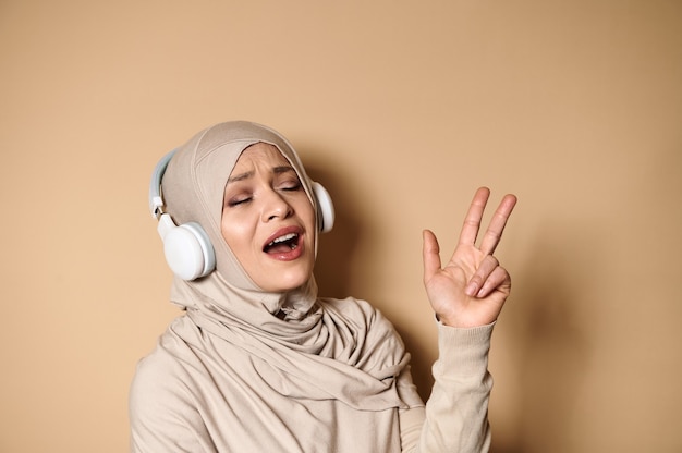 Gorgeous Muslim woman in hijab listening to the music in headphones,