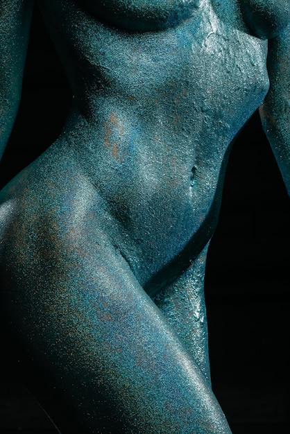 Gorgeous naked brunette posing painted in turquoise sequins.