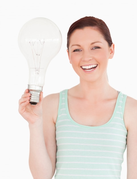 Gorgeous red-haired female holding a light bulb while standing