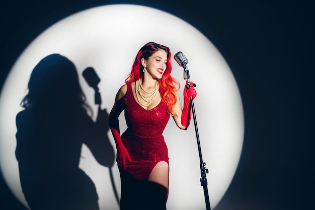 Photo gorgeous red haired woman with retro microphone singing on stage