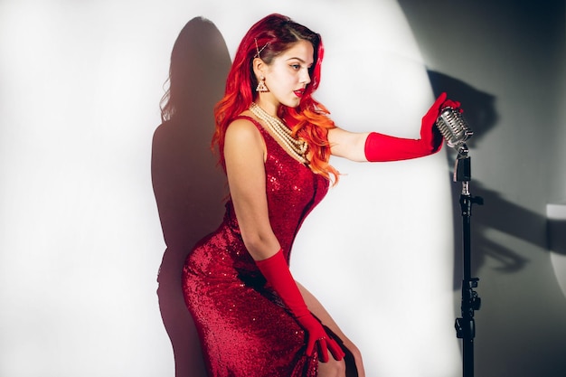 Gorgeous red haired woman with retro microphone singing on stage