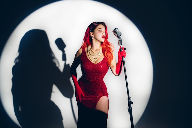 Photo gorgeous red haired woman with retro microphone singing on stage