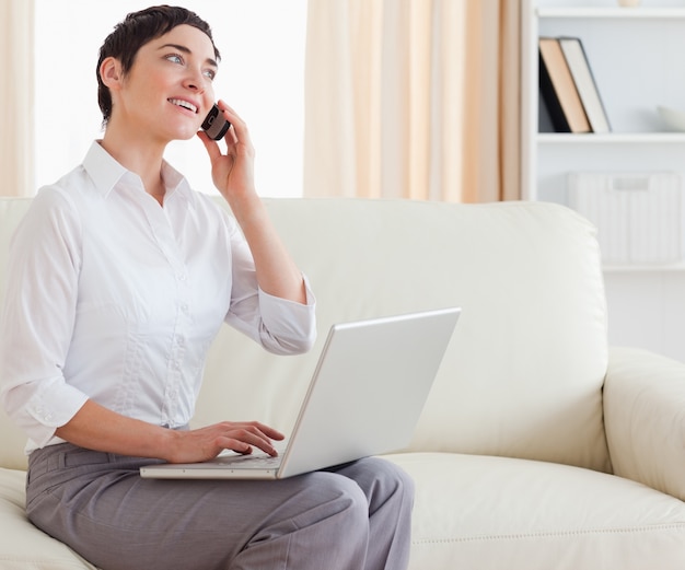 Splendida donna dai capelli corti con un computer portatile e un telefono