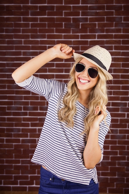 Gorgeous smiling blonde hipster posing with straw hat